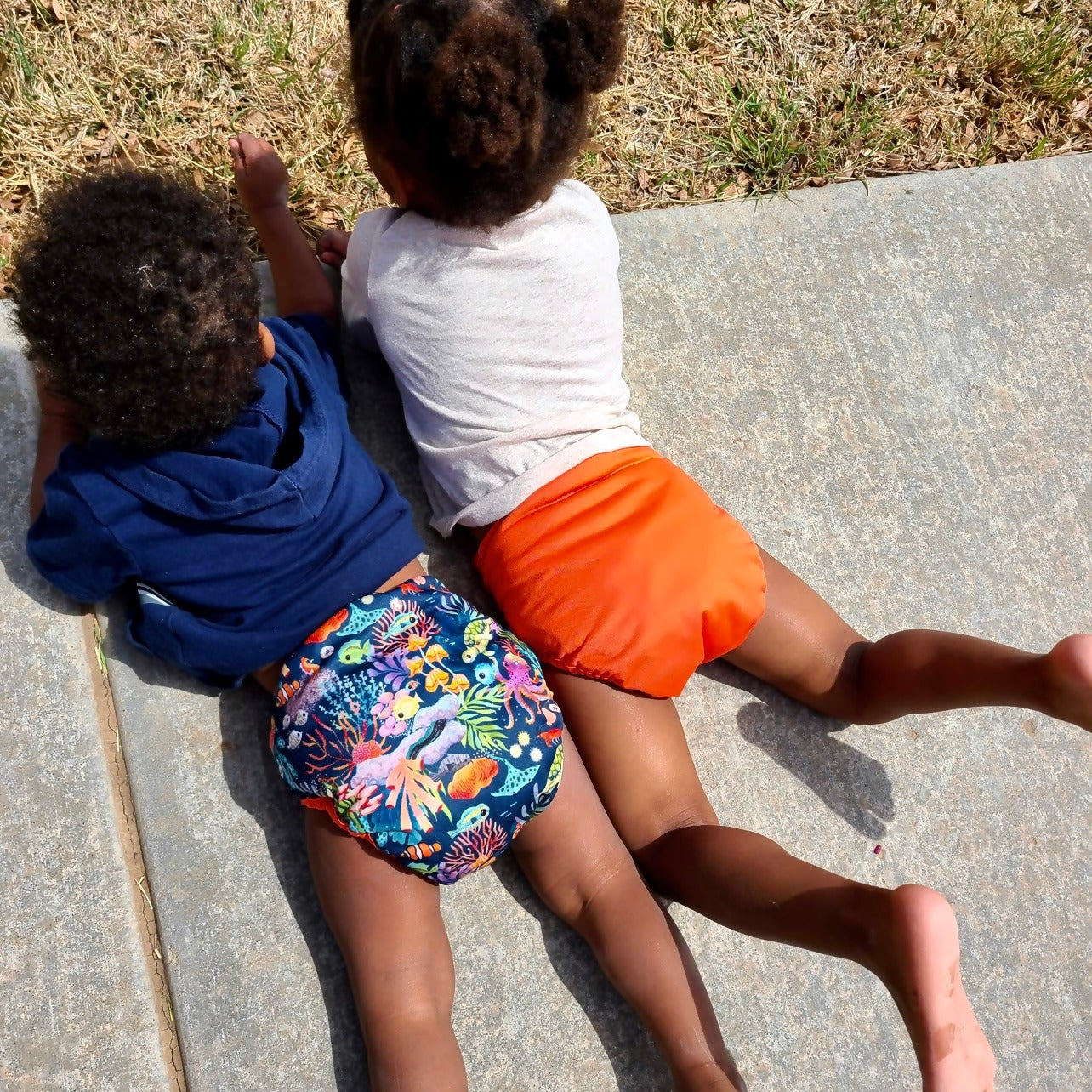image of two children in orange and sea life diapers