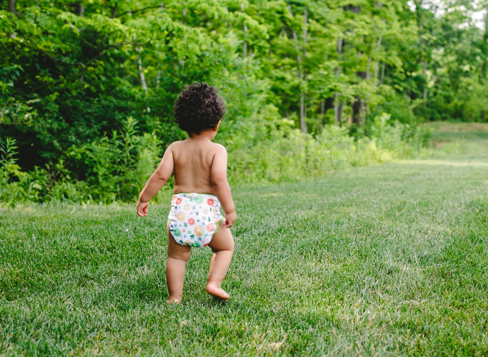 child running in a diaper in a yard