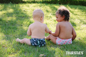 Image of babies sitting in grass in diapers