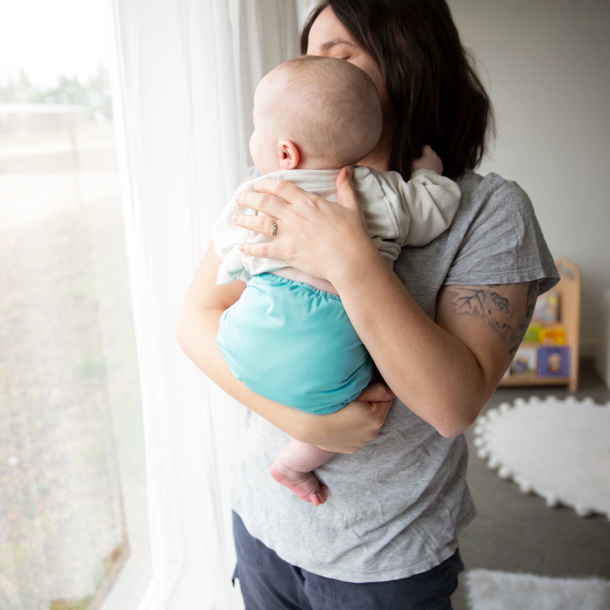 Image of a mom and her baby wearing a Thirsties Duo Wrap with snap closures in Lagoon